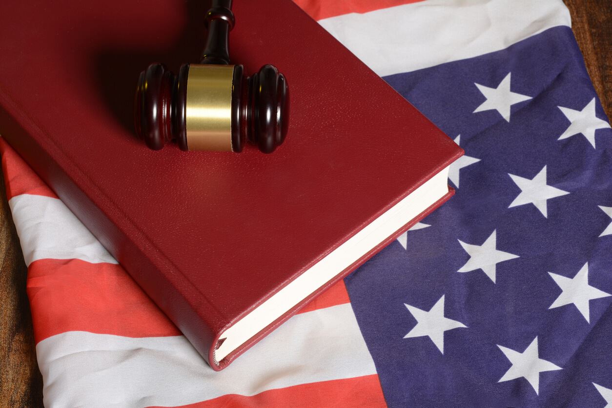 Gavel on top of a law book, which are both on top of a folded American flag.